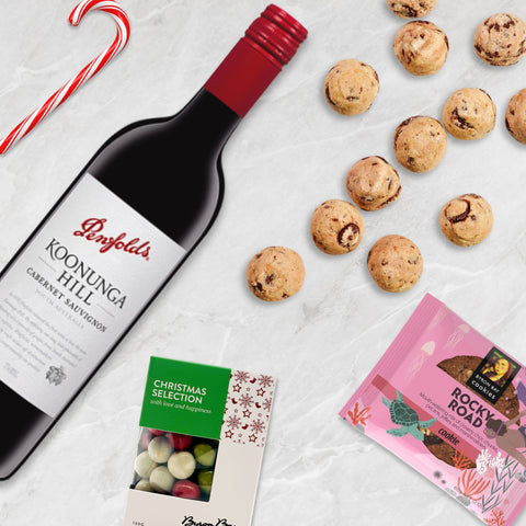 Penfolds Koonunga Hill wine bottle with cookies and candy on a light surface