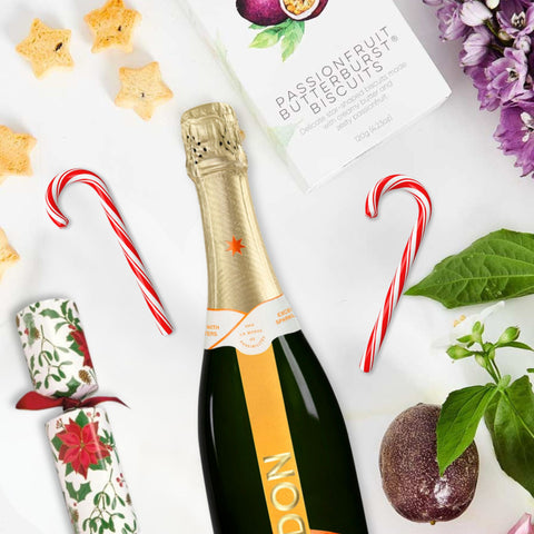 Bottle of Chandon Garden Spritz with Christmas-themed items on a white background