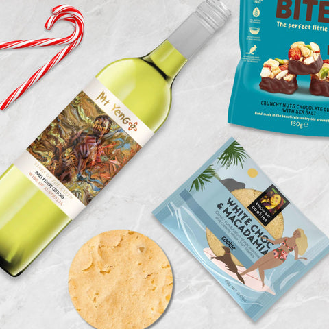 Wine bottle, cookies, and chocolate bites on a textured surface