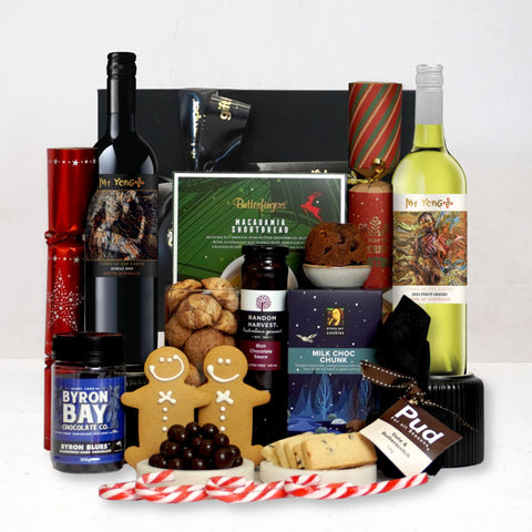 Gourmet gift basket with wine, xmas treats, and other snacks on a white background