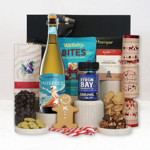Assorted gift items including a bottle of prosecco, chocolate, and cookies on a white background