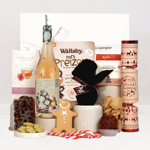 Assorted gift items including a bottle of Rosé, cookies, and xmas snacks on a white background