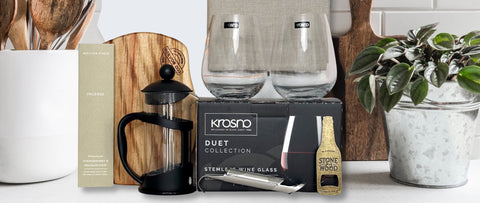 Krosno stemless wine glasses with gift hamper packaging and household items on a kitchen counter.