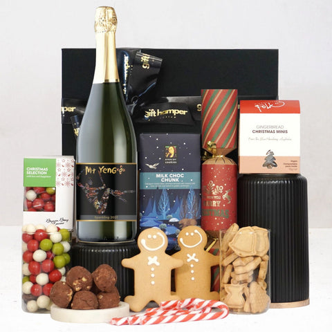 Gourmet gift basket with sparkling wine, cookies, and various treats on a white background